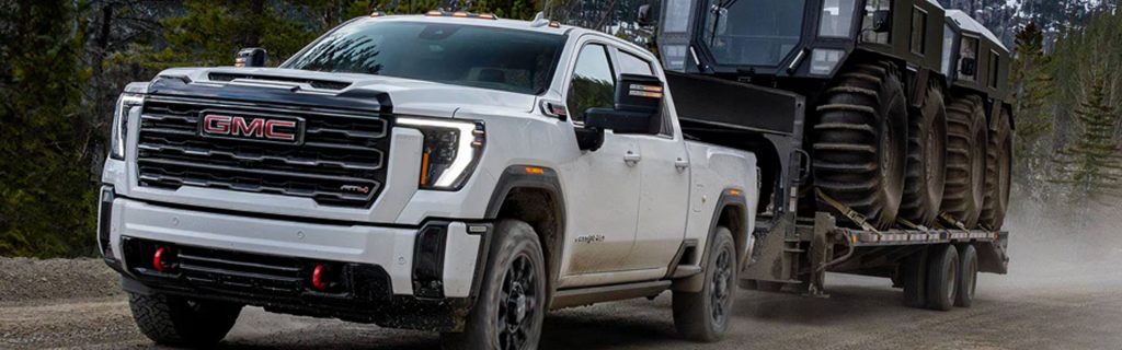 A GMC truck towing a large vehicle on a rugged terrain