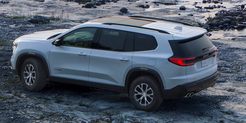 GMC SUV parked on rocky terrain with panoramic roof and rugged off-road tires.