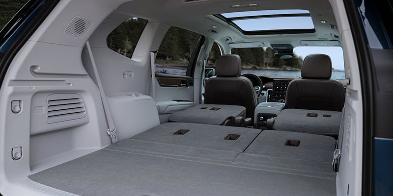 SUV interior with rear seats folded flat, showing spacious cargo area and panoramic sunroof.