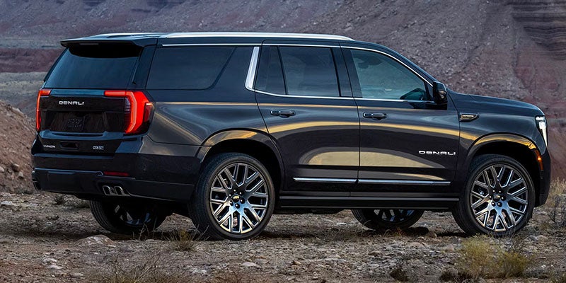 GMC Yukon parked in a rocky desert landscape during sunset.
