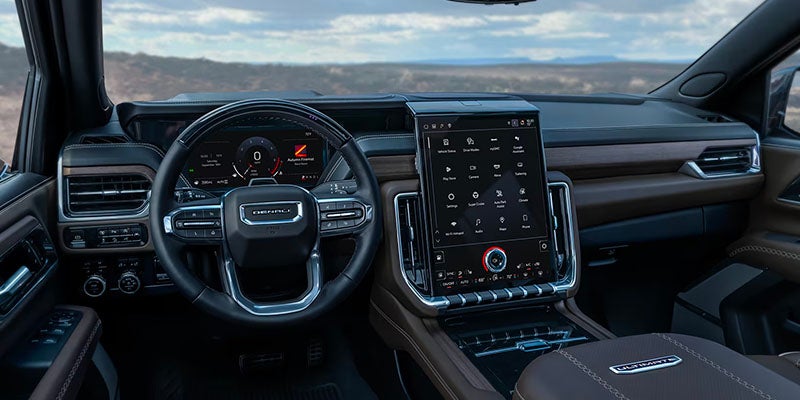 Luxurious GMC Yukon interior with digital dashboard and large touchscreen infotainment system.