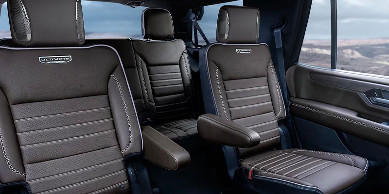 Luxurious brown leather captain’s chairs in GMC Yukon with “Ultimate” badging and stitching